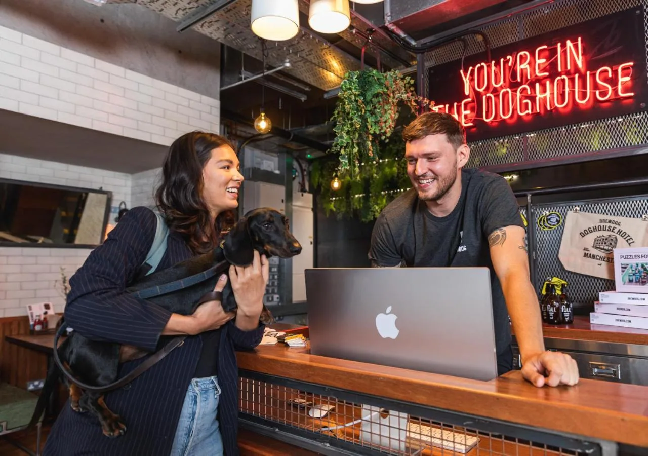 a man and a woman with a dog in front of a laptop at BrewDog DogHouse Manchester in Manchester