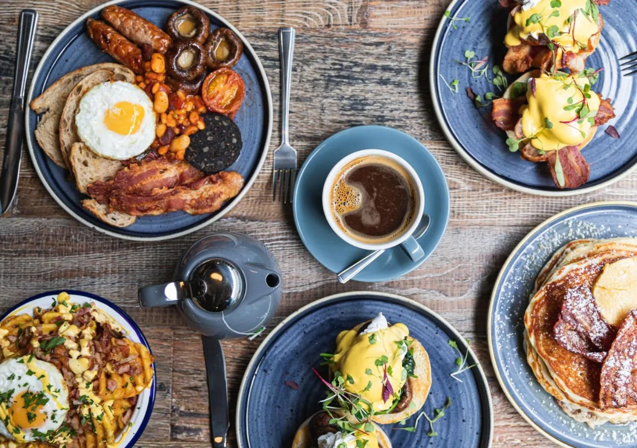 a table with plates of breakfast foods and a cup of coffee at BrewDog DogHouse Manchester in Manchester