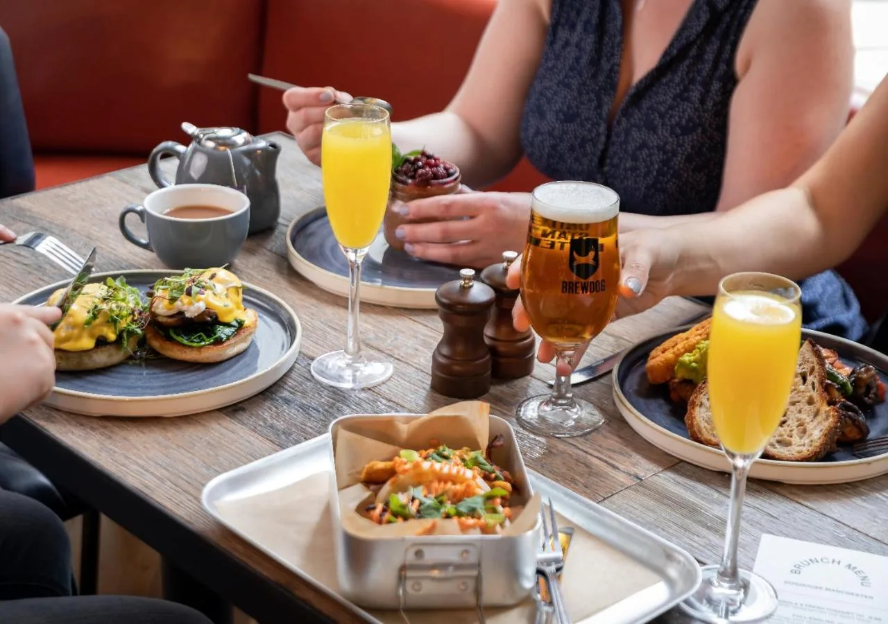 a group of people sitting at a table with food and drinks at BrewDog DogHouse Manchester in Manchester